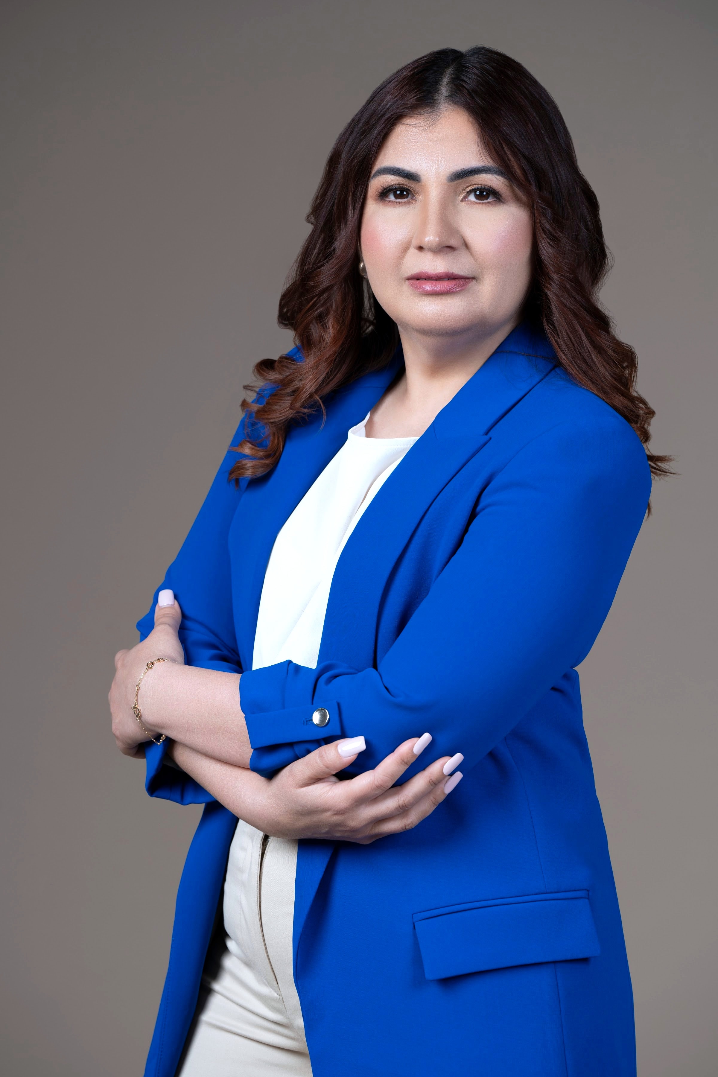 Krissia García, consultora empresarial, de brazos cruzados y mirando a cámara, con blazer azul